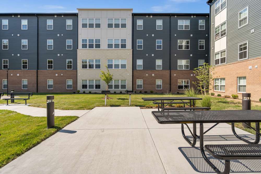 Modern apartment community with green lawn, picnic tables, and landscaped areas at Sparrow Ridge in Hebron, Kentucky