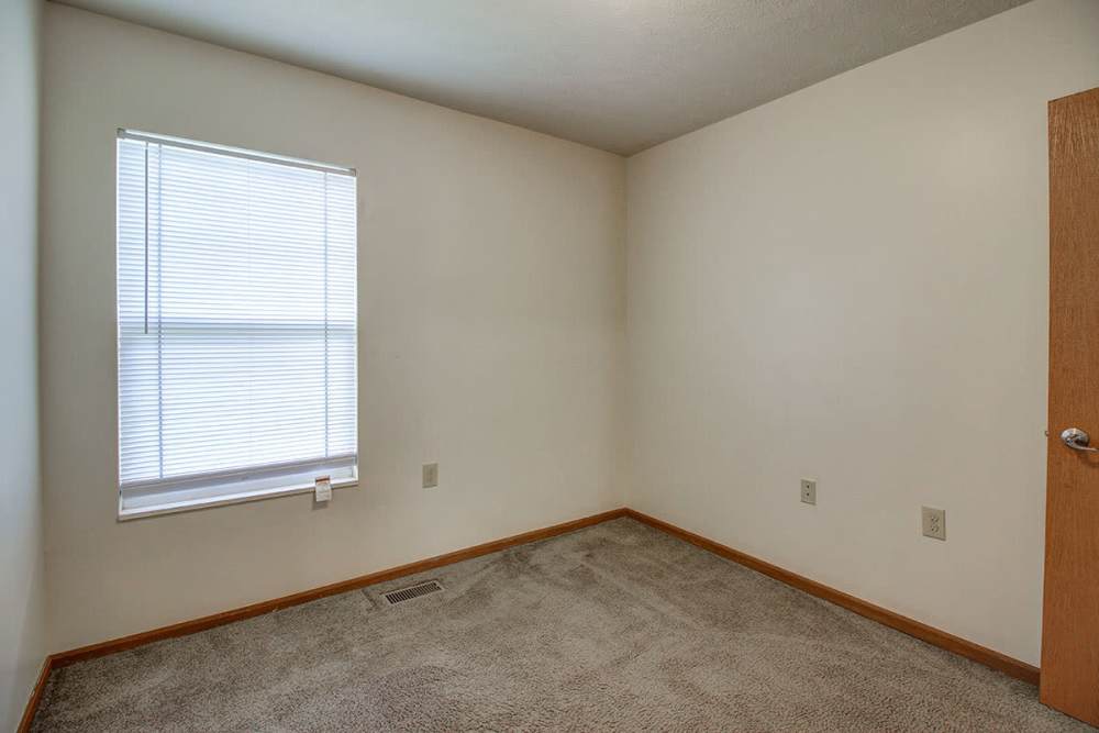 Empty room with beige carpet, window with blinds, and light-colored walls at Sterling Greene in Fayetteville, Tennessee
