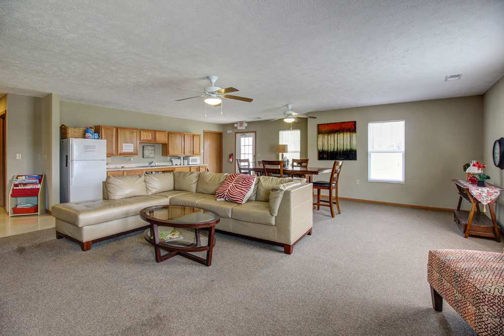 Spacious living area with a sectional sofa, dining table, and kitchen featuring wood cabinetry and appliances at Sterling Greene in Fayetteville, Tennessee