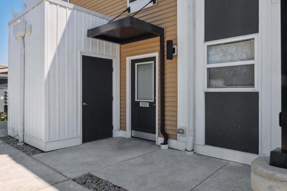 Modern apartment entrance with a sleek black door and light wood accents at Winston Commons in Pontiac, Michigan