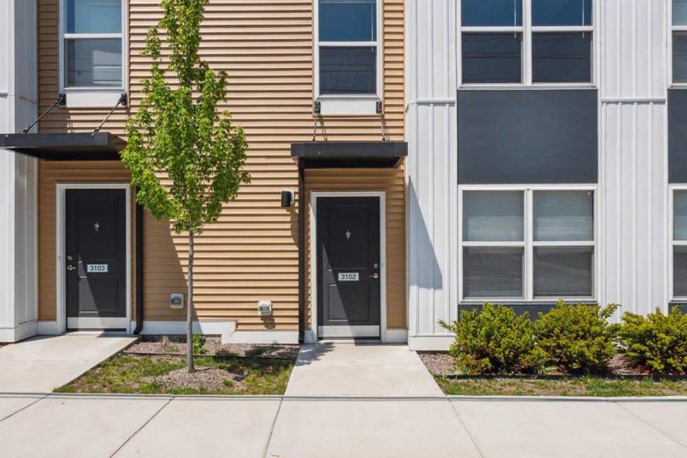 Two modern apartment entrances with landscaped greenery and concrete walkways at Winston Commons in Pontiac, Michigan