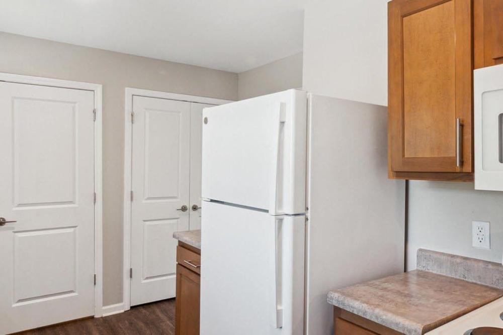 Bright kitchen with white refrigerator, wood-style cabinets, and modern countertops at Winston Commons in Pontiac, Michigan