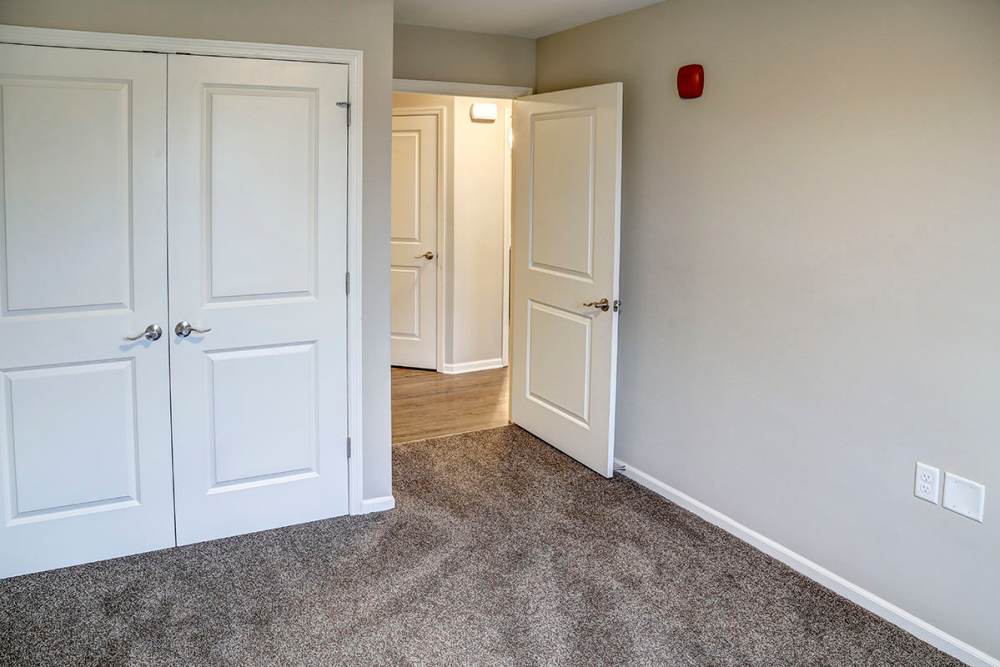Carpeted room with double doors leading to a hallway and wood-style flooring visible beyond at Tristan Ridge in Eminence, Kentucky