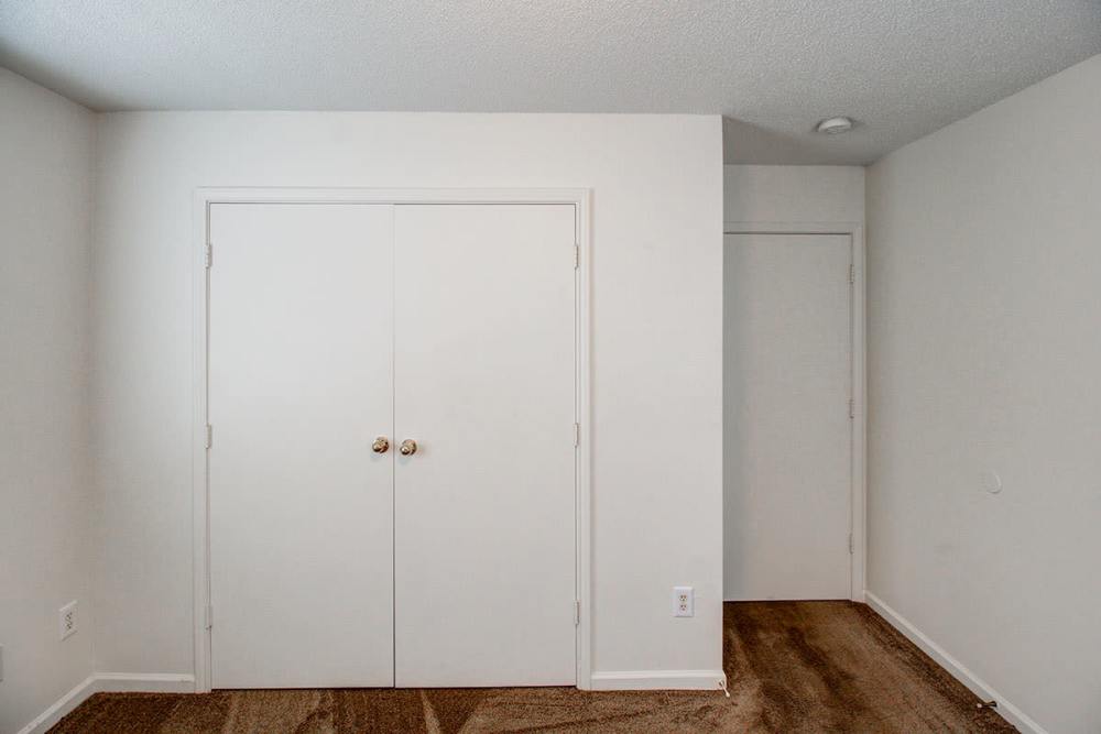 Empty room with beige carpet, two closed white doors, and a light-colored wall at Valley View Gardens in Dunlap, Tennessee
