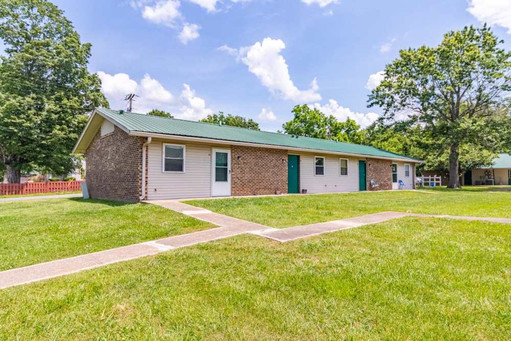 Single-story apartment community with green roofs, grassy lawns, and paved walkways between units at Walnut Street Apartments in Dickson, Tennessee