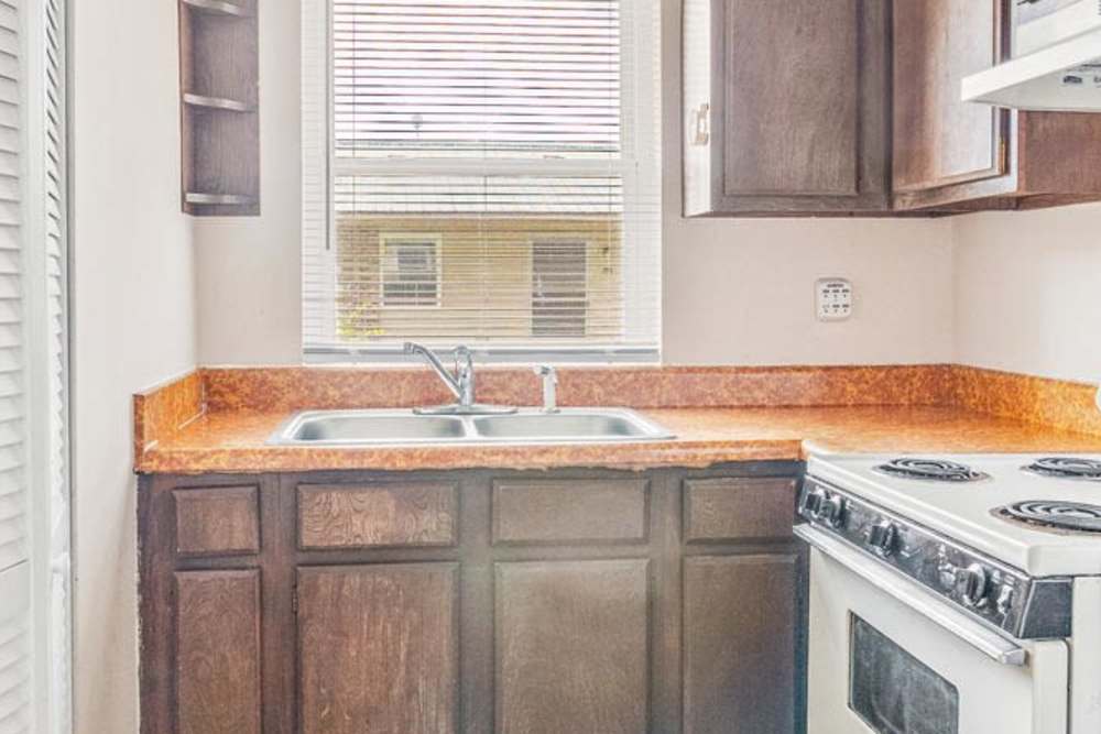 Cozy kitchen with dark wood cabinets, stainless steel stove, and window for natural light at Walnut Street Apartments in Dickson, Tennessee