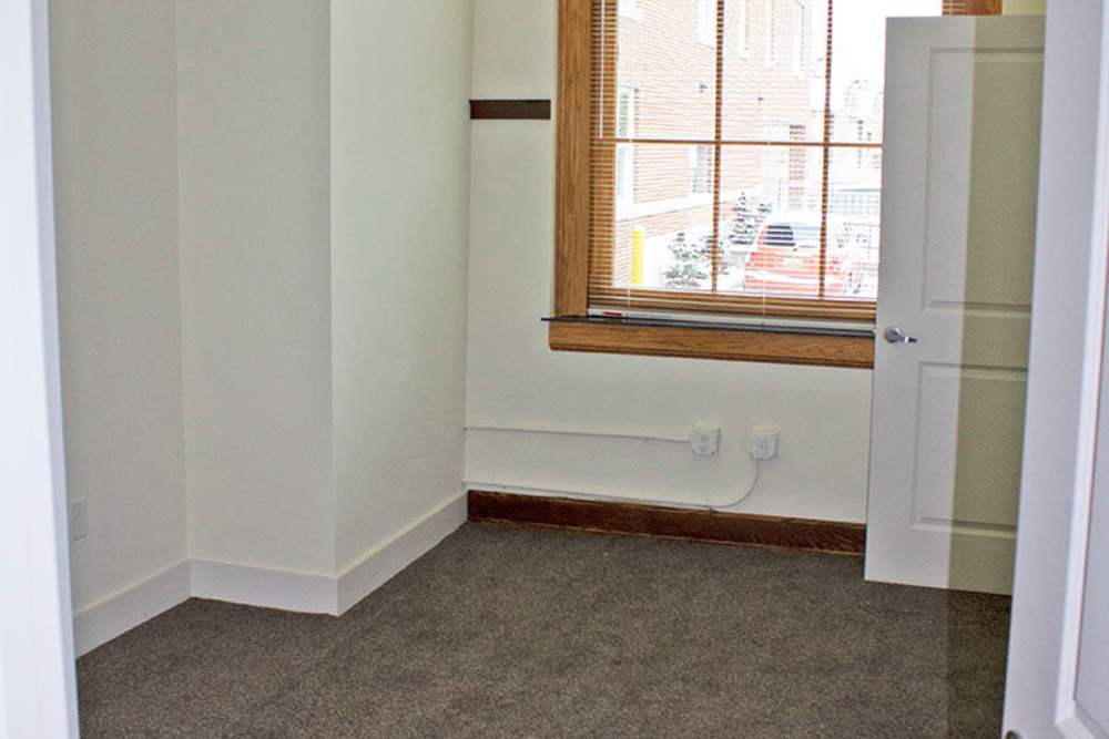 Cozy room with carpet flooring and large window letting in natural light at Lincoln House in Owosso, Michigan