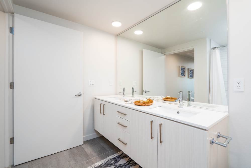 Bright bathroom with double vanity, sleek fixtures, large mirror, and modern decor at Exhibit at J Town in San Jose, California