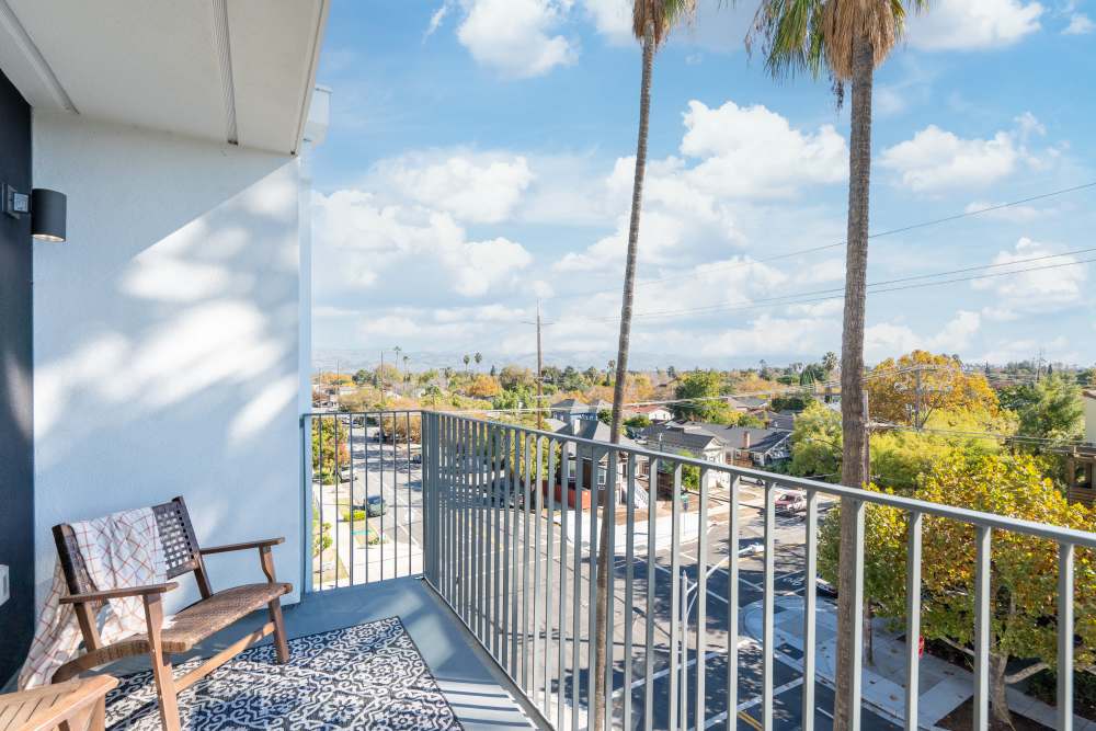 Balcony with seating and palm trees overlooking a vibrant neighborhood and blue sky at Exhibit at J Town in San Jose, California