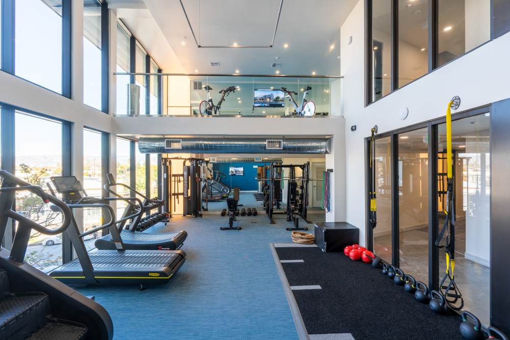 Modern fitness center with large windows, treadmills, weights, and workout equipment for active lifestyle at Exhibit at J Town in San Jose, California