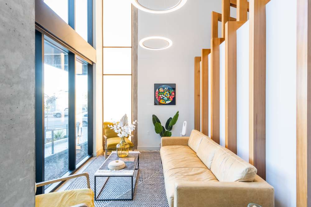 Bright lounge area with large windows, modern furniture, and decorative plants, inviting atmosphere at Exhibit at J Town in San Jose, California