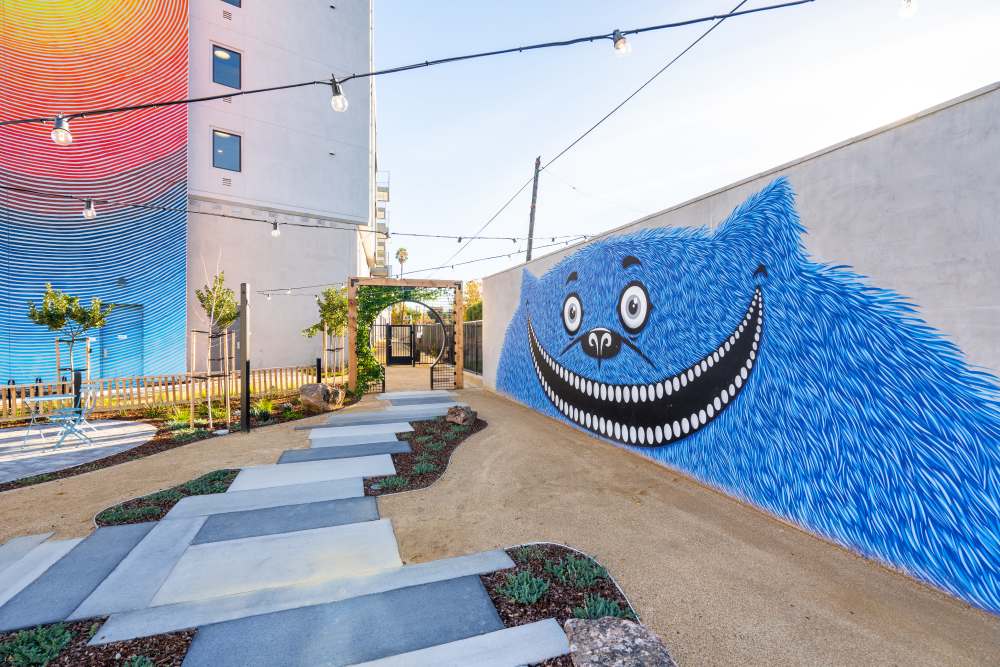 Colorful mural on a pathway surrounded by greenery and decorative lighting at Exhibit at J Town in San Jose, California
