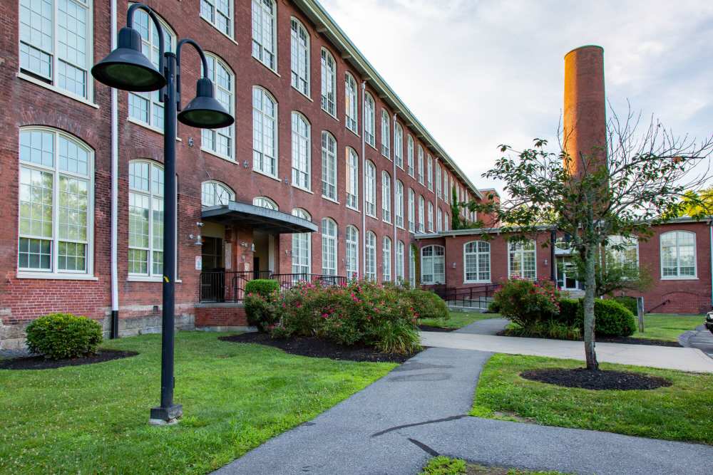 Exterior view of the community building with lawn at Robertson on the River in Taunton, Massachusetts
