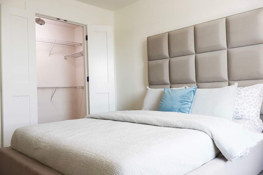 Modern bedroom with plush bedding and closet space at Copper Trail Townhomes in Owasso, Oklahoma
