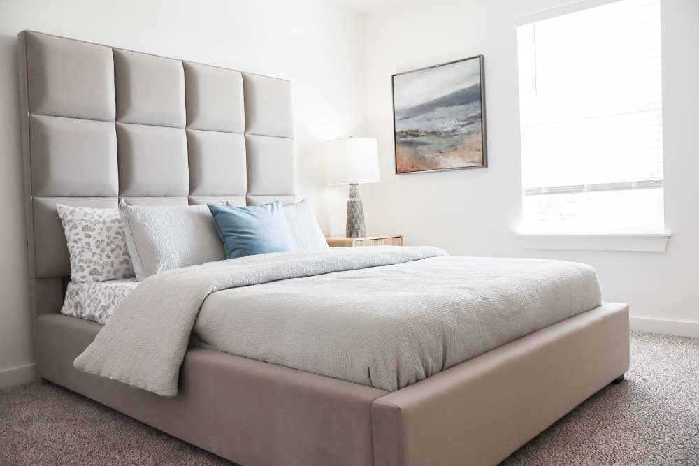Modern bedroom with plush headboard and natural light at Copper Trail Townhomes in Owasso, Oklahoma