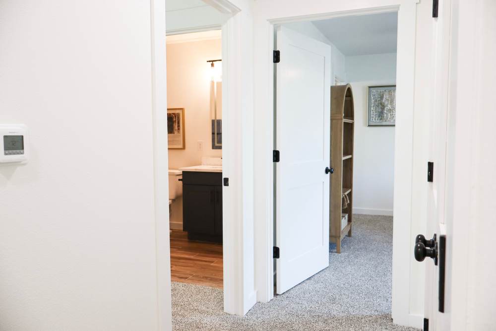 Bright hallway with modern decor and carpeted floor at Copper Trail Townhomes in Owasso, Oklahoma