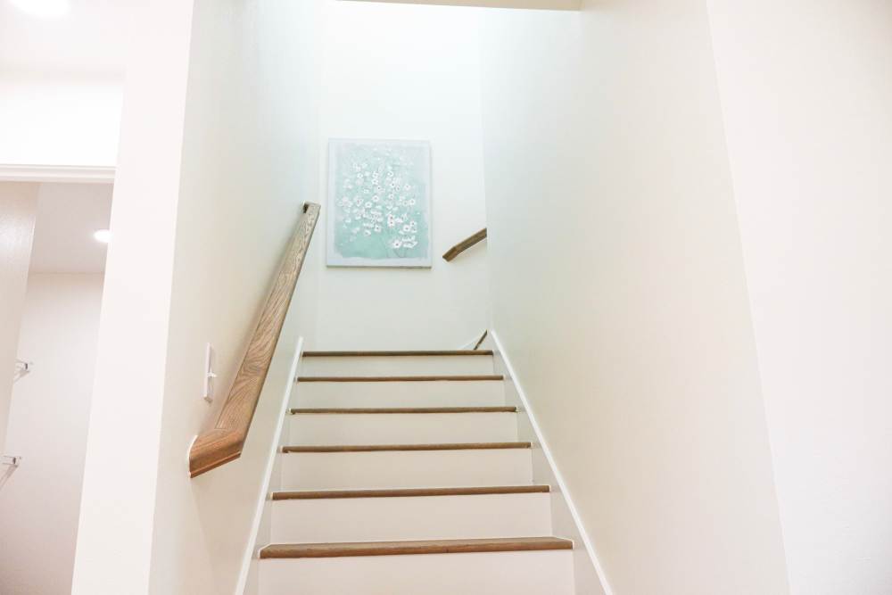 Staircase with wood-style flooring and wall art at Copper Trail Townhomes in Owasso, Oklahoma