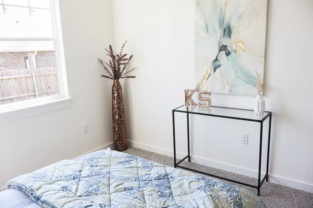 Bright bedroom with decorative plant and art at Copper Trail Townhomes in Owasso, Oklahoma