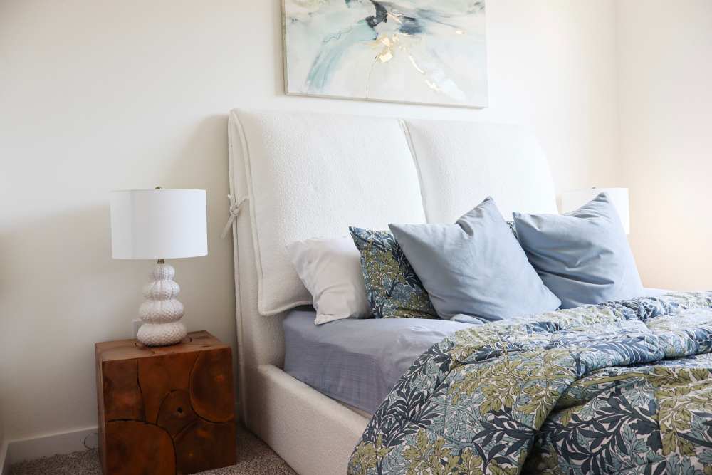 Stylish bedroom with cozy bedding and lamps at Copper Trail Townhomes in Owasso, Oklahoma