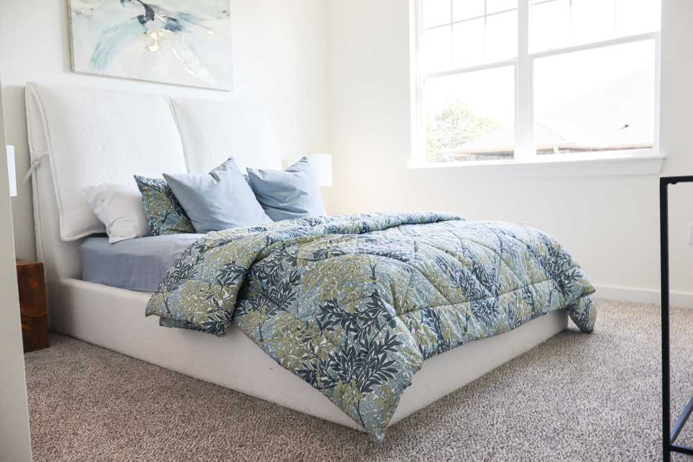 Cozy bedroom with plush bedding and natural light at Copper Trail Townhomes in Owasso, Oklahoma