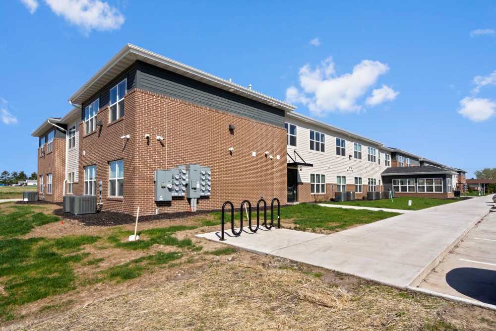 Modern apartment community with brick exterior, landscaped grounds, and bike racks visible at Chandler Pointe in Wilton, Iowa