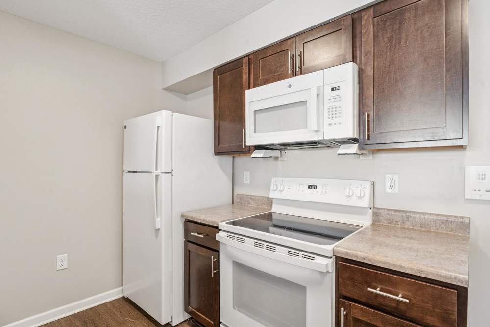 Modern kitchen with white appliances, granite countertops, and dark wood cabinetry at Johnston Crossing I in Johnston, Iowa