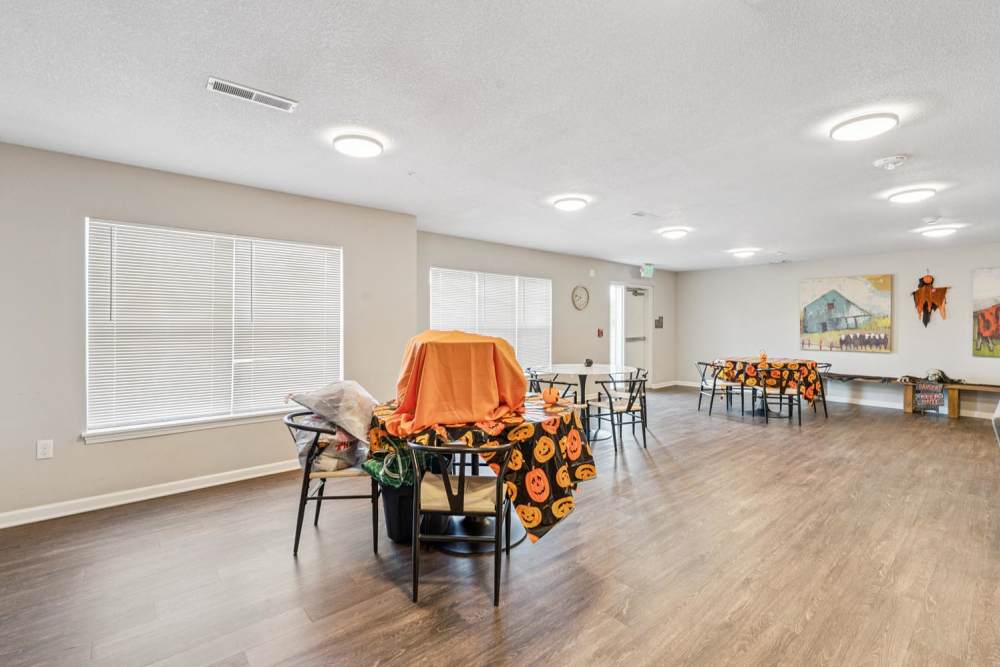 Spacious community room with wood-style flooring and decorated tables for seasonal events at Johnston Crossing I in Johnston, Iowa