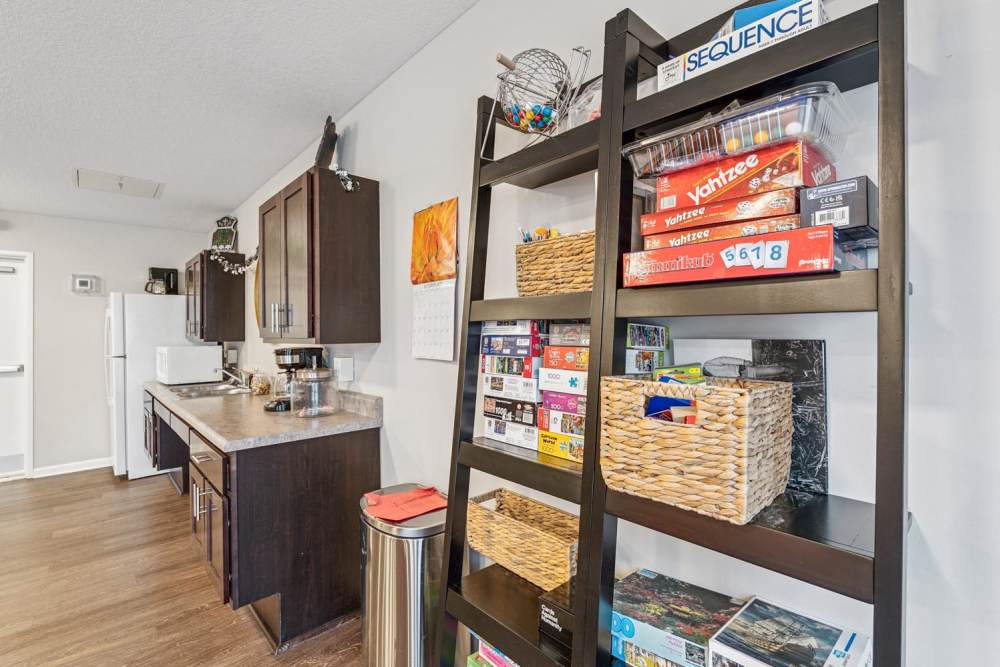 Modern kitchen with dark cabinetry, stainless steel appliances, and wood-style flooring, featuring a game shelf at Johnston Crossing I in Johnston, Iowa