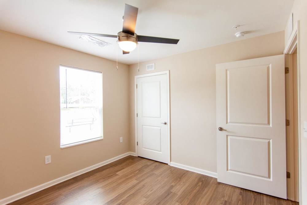 Bright bedroom with wood-style flooring, ceiling fan, and large window for natural light at Palatine Meadows in New Bern, North Carolina