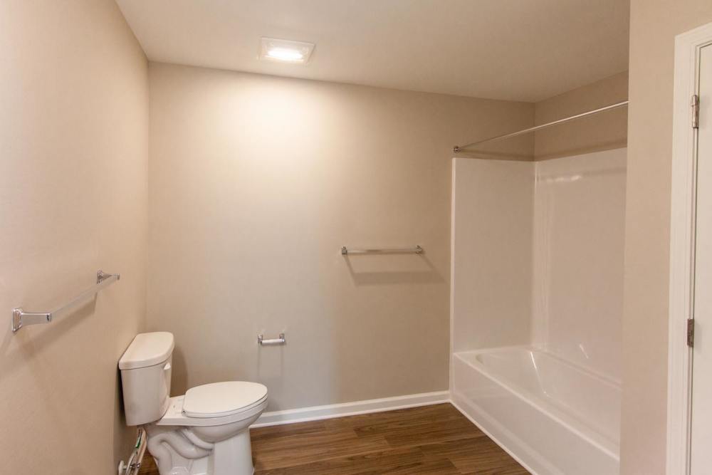 Spacious bathroom with wood-style flooring, bathtub, and modern toilet fixtures at Palatine Meadows in New Bern, North Carolina