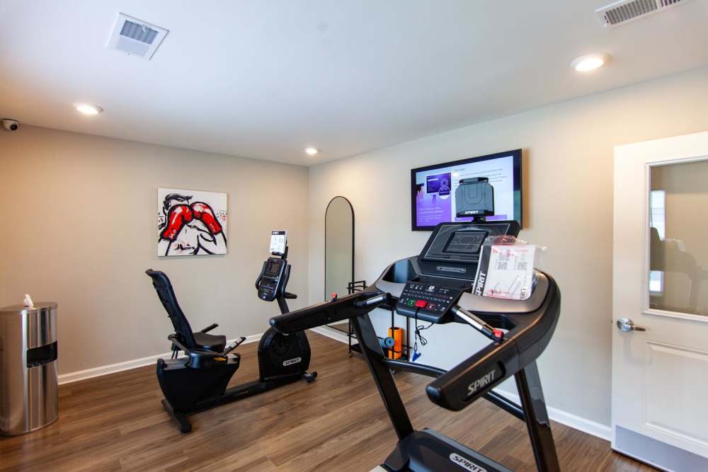 Fitness center with wood-style flooring, treadmill, recumbent bike, and motivational artwork on the wall at Palatine Meadows in New Bern, North Carolina