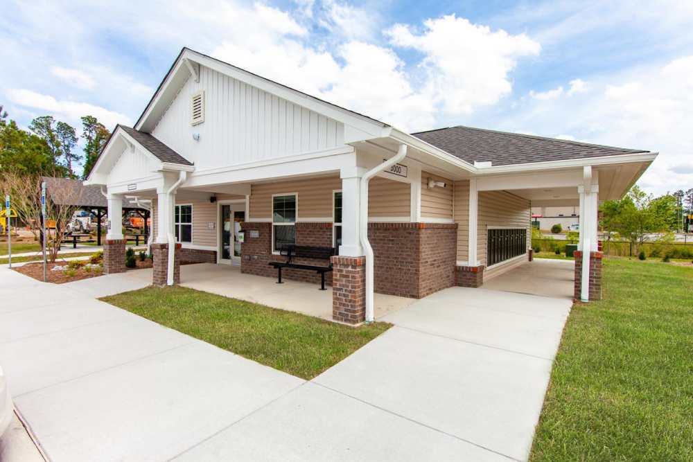 Community clubhouse with covered porch and seating area surrounded by landscaped grounds at Palatine Meadows in New Bern, North Carolina