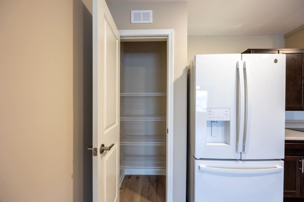 Bright kitchen featuring stainless steel refrigerator and spacious pantry with wire shelving at Pender Crossing in Wilson, North Carolina