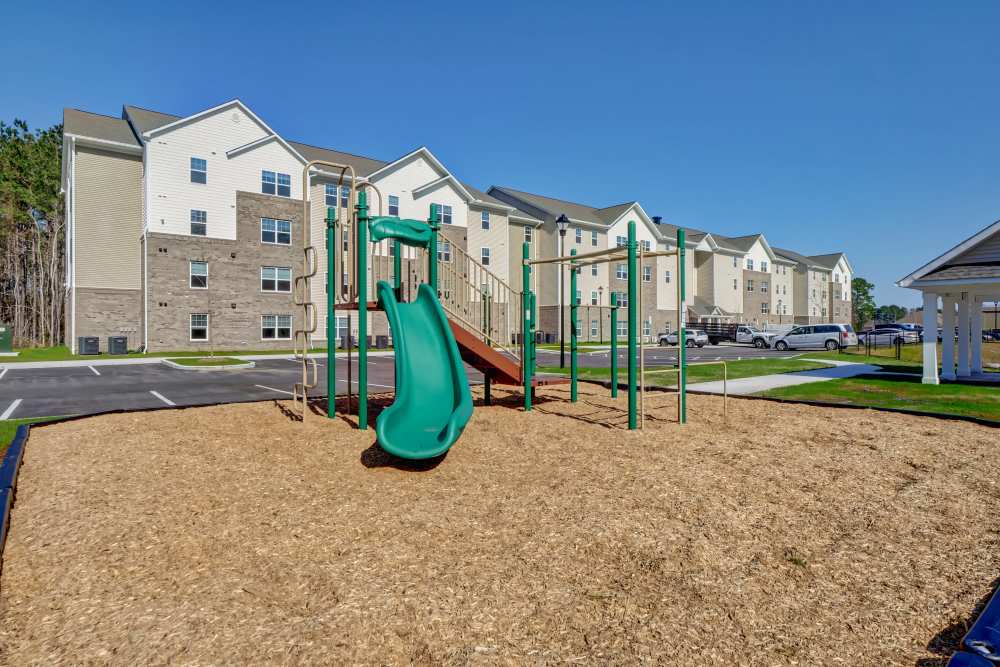 Playground with slide and climbing structure near apartment buildings and parking area at Tate Commons in New Bern, North Carolina