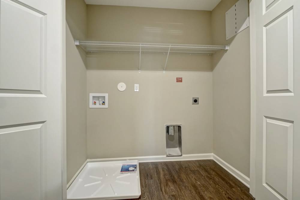 Spacious laundry room with wood-style flooring and shelving for storage at Tate Commons in New Bern, North Carolina