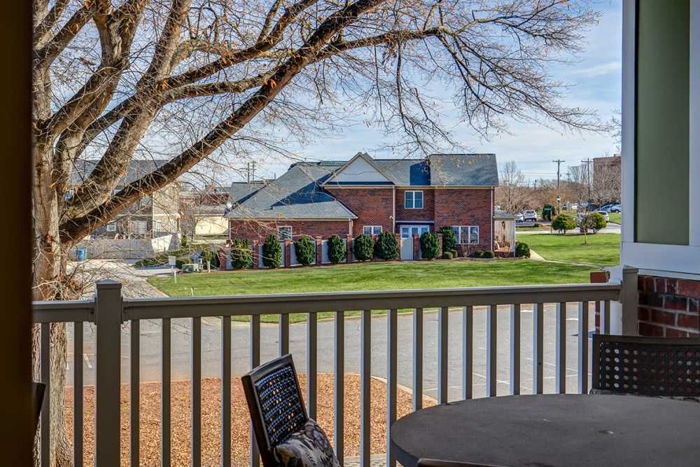 View from balcony overlooking landscaped grounds and nearby buildings with a tree in the foreground at Viewmont Square in Hickory, North Carolina