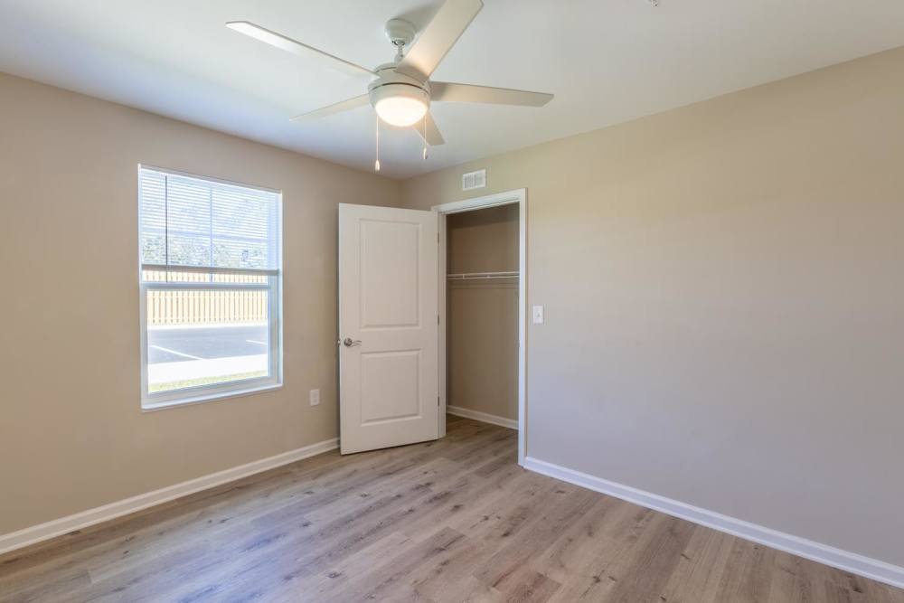 Bright bedroom with wood-style flooring, ceiling fan, and large window for natural light at Clemons Greene in Lexington, South Carolina