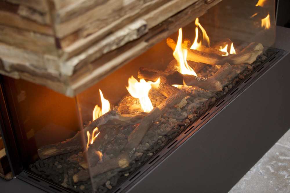 Modern gas fireplace with glowing flames and decorative logs in a sleek design at Alamitos on 4th in Long Beach, California