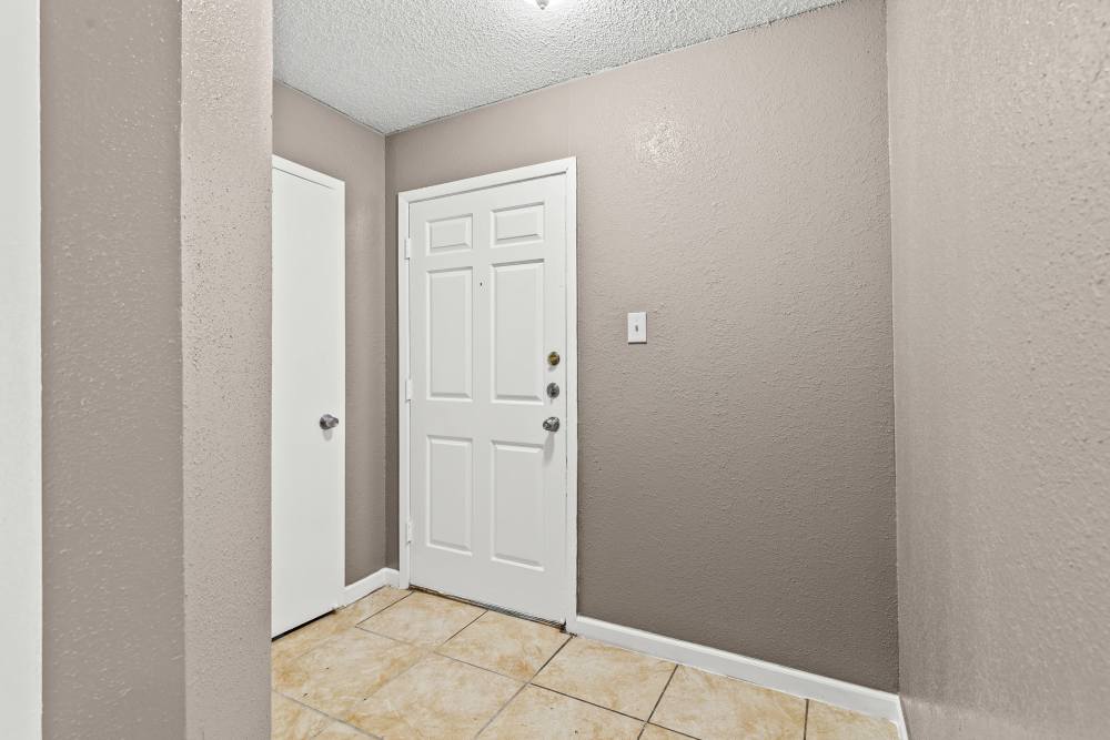 Welcoming entryway with tile flooring and neutral wall colors, featuring a white front door at Towne East Village Apartment Homes in Converse, Texas
