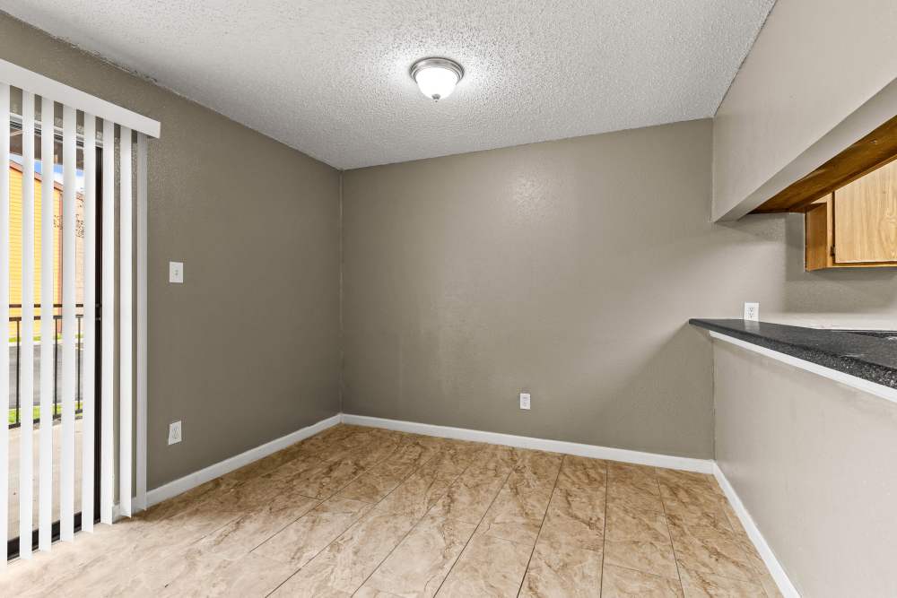 Open layout living space with wood-style flooring and sliding glass door to outdoor patio at Towne East Village Apartment Homes in Converse, Texas