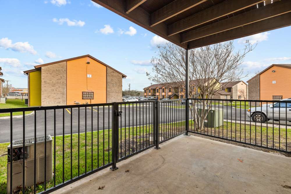 Gated patio view overlooking landscaped grounds and nearby apartment buildings at Towne East Village Apartment Homes in Converse, Texas