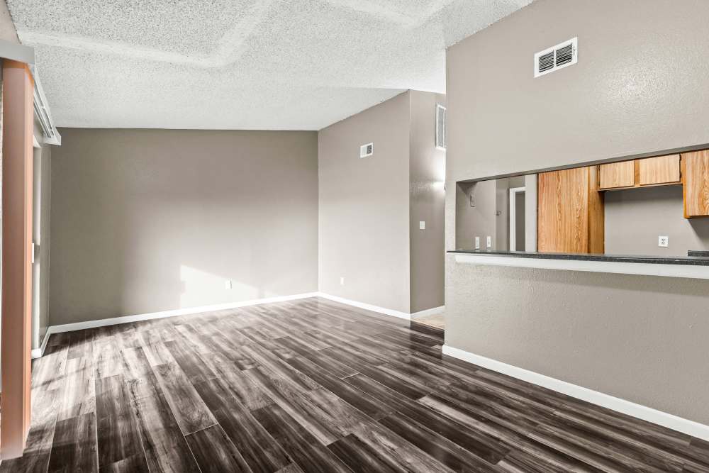 Open layout with wood-style flooring and kitchen bar area featuring wooden cabinets at Towne East Village Apartment Homes in Converse, Texas