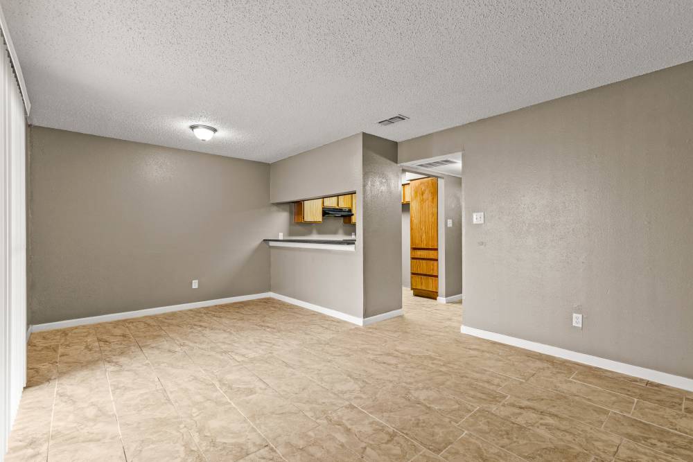 Spacious living area with tile flooring and open layout leading to kitchen at Towne East Village Apartment Homes in Converse, Texas