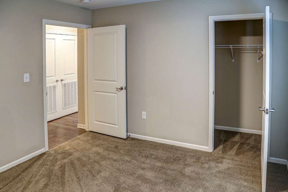 Cozy bedroom with carpeted flooring, two doors leading to closets, and neutral wall colors at Brea's Crossing Senior Living II in Shelbyville, Kentucky