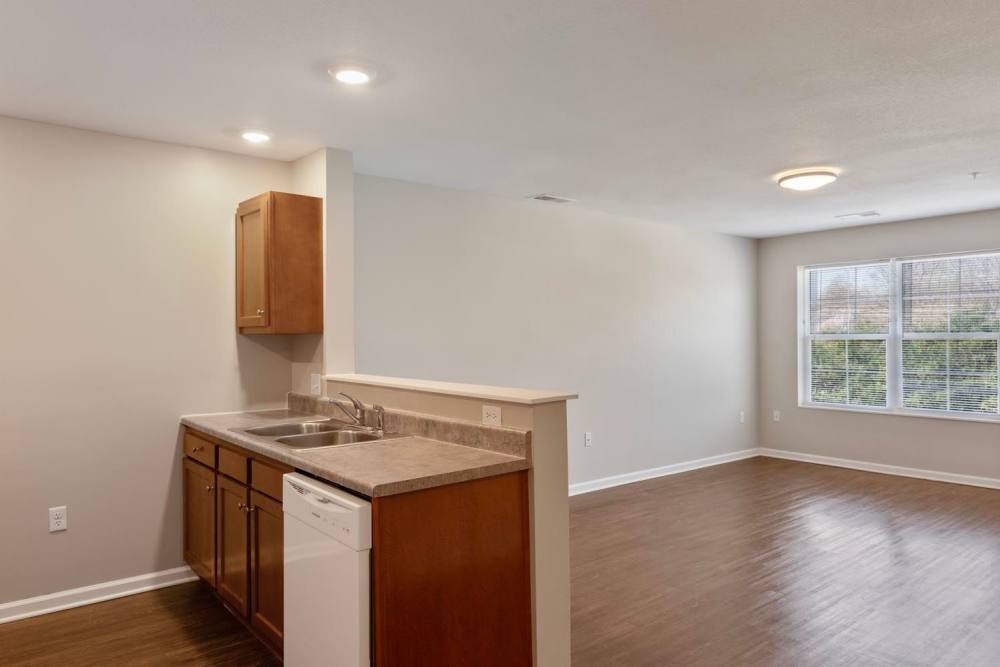 Open layout kitchen with granite countertops and stainless steel appliances, wood-style flooring in living area at Kirkman Terrace in Hopkinsville, Kentucky