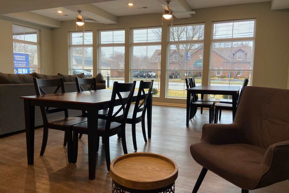 Bright community lounge with wood-style flooring, large windows, and modern furniture for social gatherings at Kirkman Terrace in Hopkinsville, Kentucky