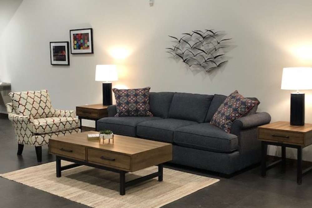 Cozy living room with a blue sofa, patterned chair, and wooden coffee table at Portland School in Portland, Michigan