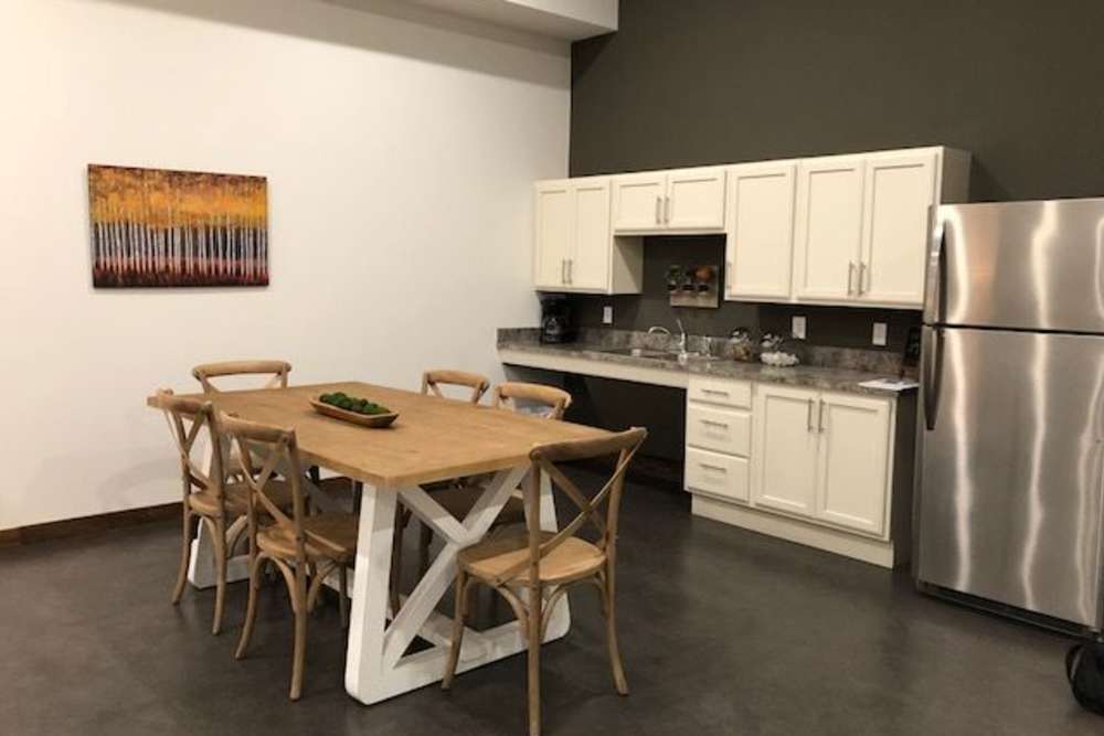 Modern kitchen with stainless steel appliances, granite countertops, and a dining table for six at Portland School in Portland, Michigan