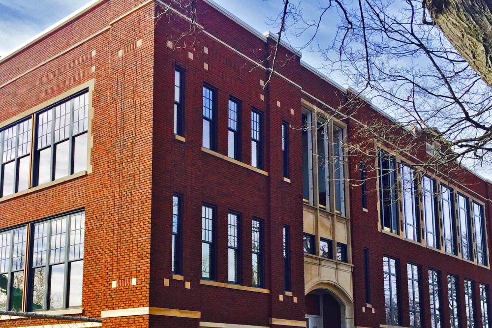 Red brick apartment building with large windows and a welcoming entrance at Portland School in Portland, Michigan