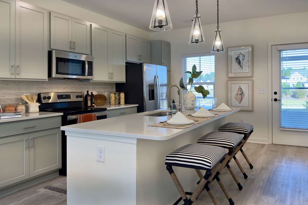 Modern clubhouse kitchen with stylish pendant lights over a breakfast bar at Encore at Westgate in Leland, North Carolina